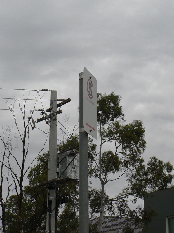 The "no stopping" sign and transformer on a power pole.